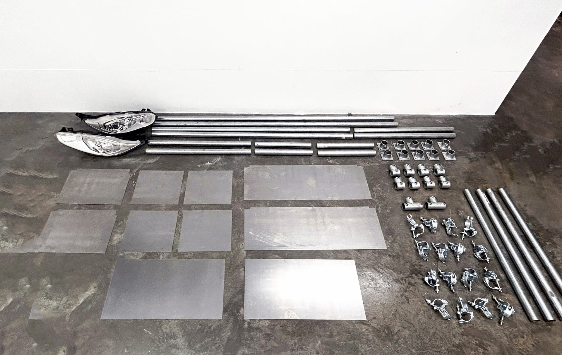 All scaffold joints and metal pieces used in the furniture are laid out on the floor, showing the materials at a glance.