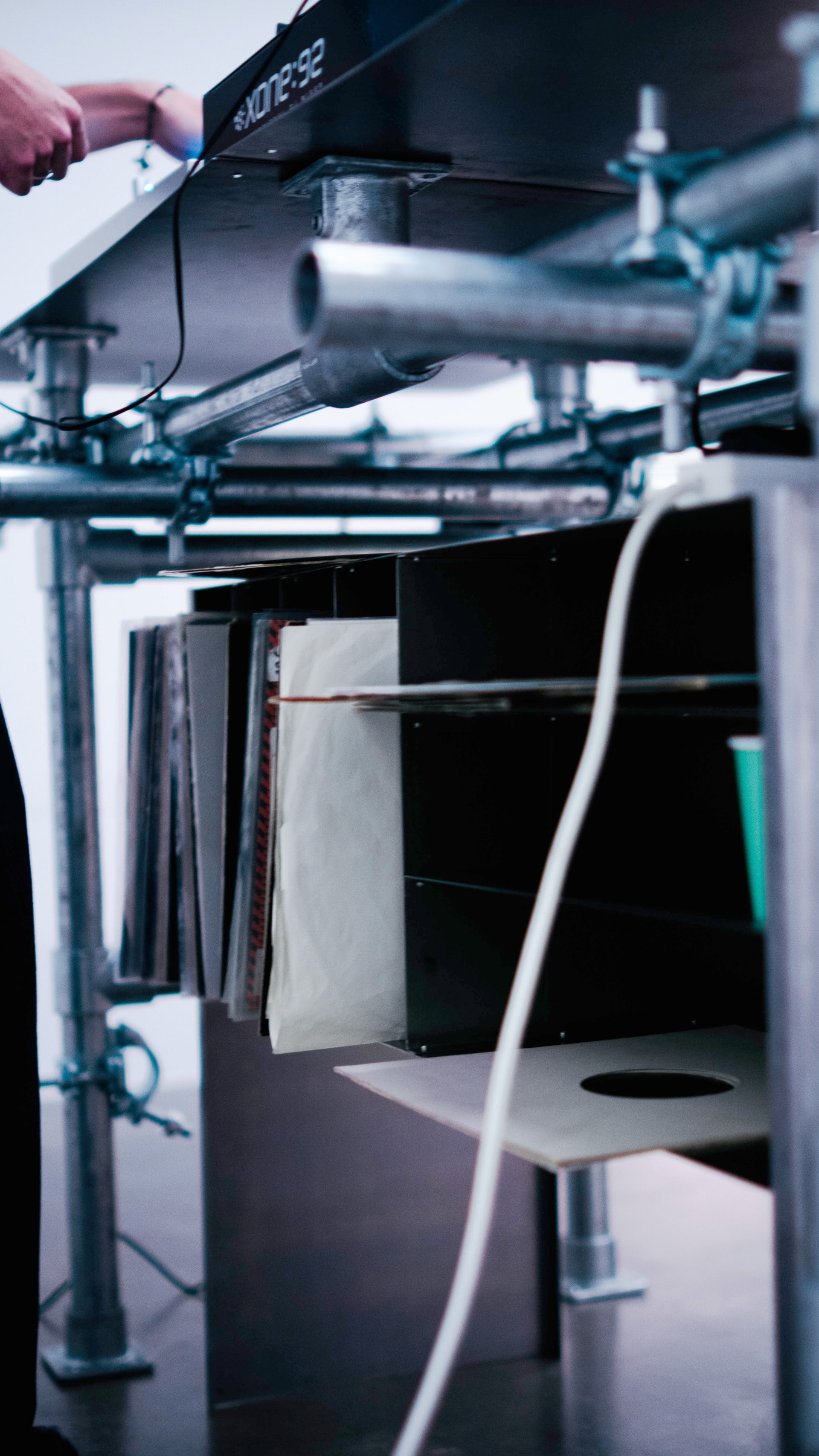 LP vinyls are stored inside a minimal metal storage unit beneath the pipe structure.