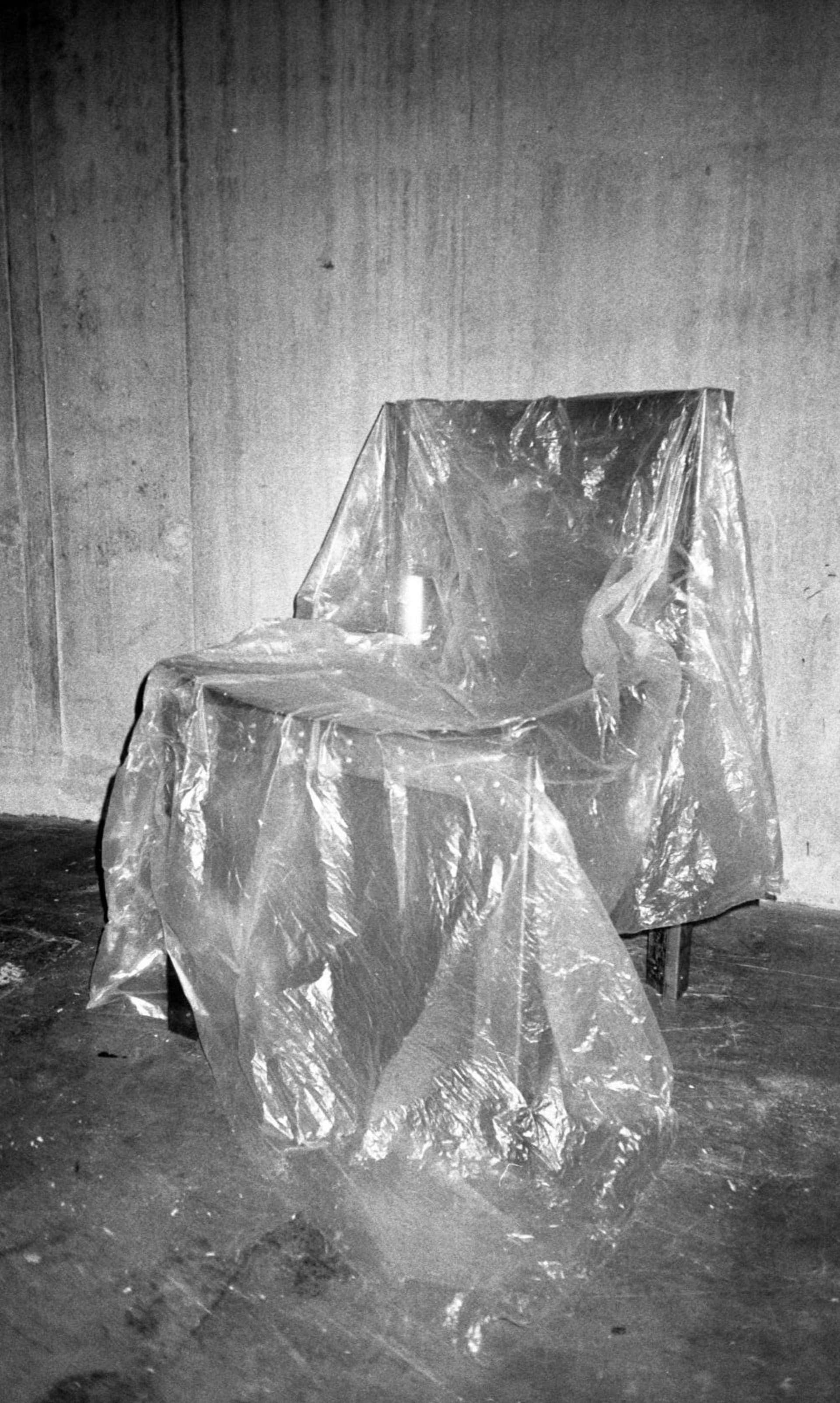 Front view of the metal chair, covered in a plastic tarp.