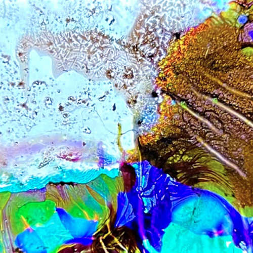 Abstract image of vivid blue, green and gold textures resembling crystalline formations under magnification.