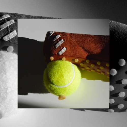 Close-up of a handcrafted shoe with a bright tennis ball attached, shown against a monochrome background.
