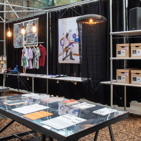 An exhibition display featuring publications, posters, boxes and clothing