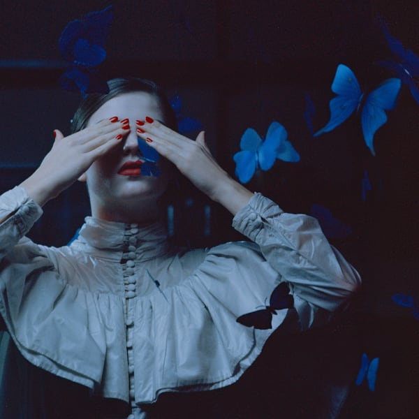 Female model with red nails covering her eyes. 