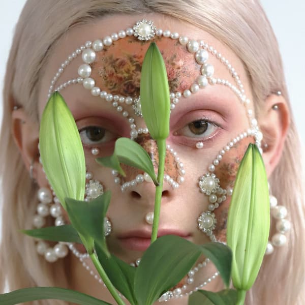 Female model with pearl facial jewellery, makeup and lilies.