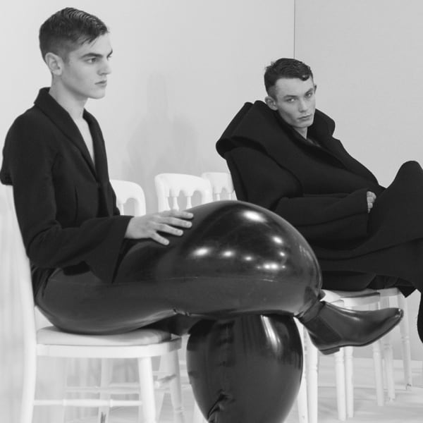 Four male models seated in loose black clothing