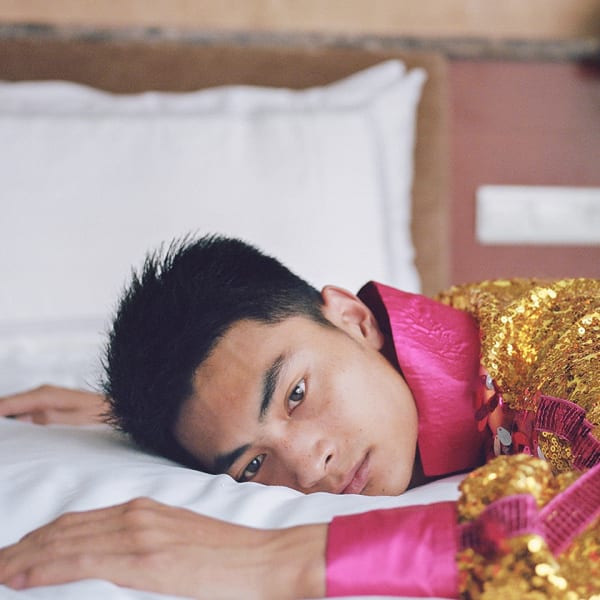 A person lying on a bed and looking straight to camera.