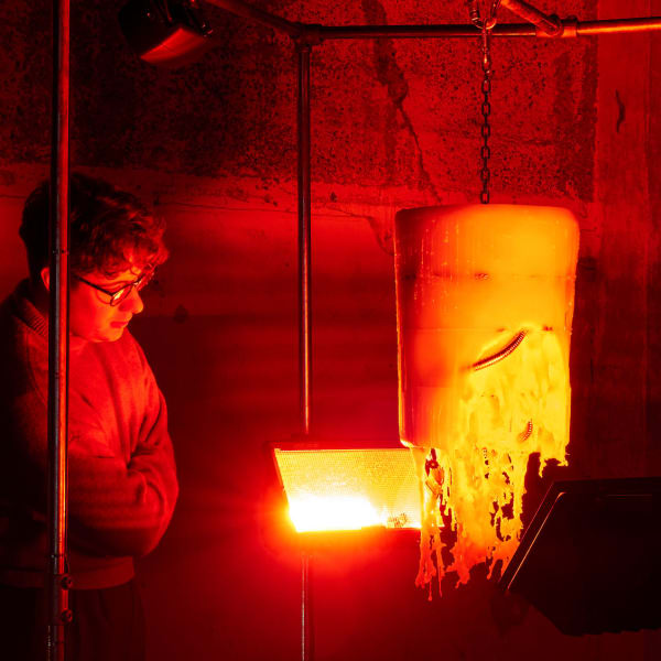 Two people look at a sculpture under a red light.