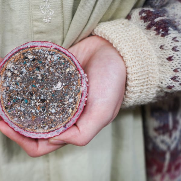 Student holding model that has been sliced in half to reveal inside showing recycled filling.