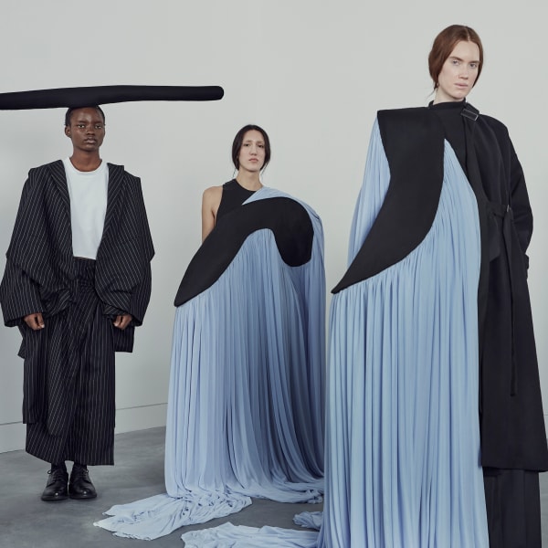 Female models wearing floaty pale blue skirts that trail across the floor.