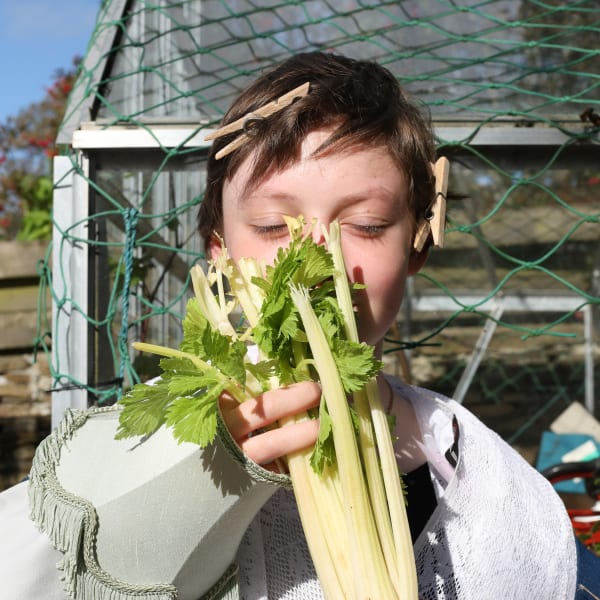 A girl holding a vegetable in front of her face 