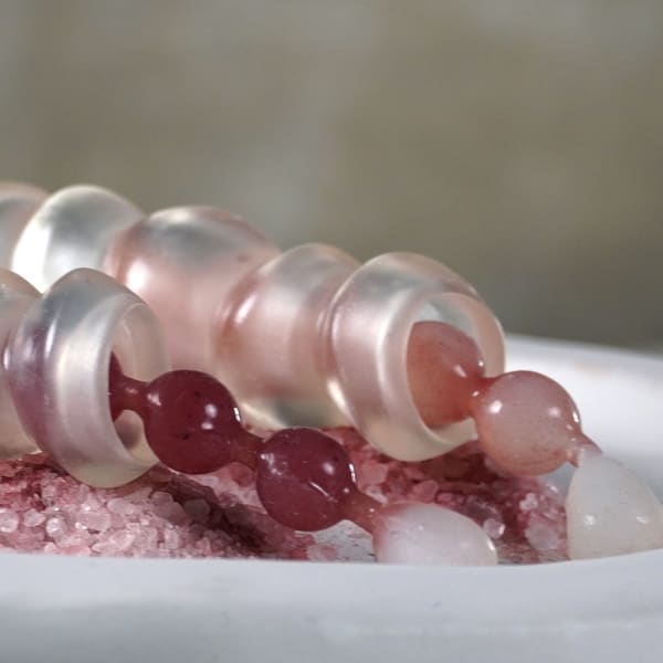Sheathed pink beads on a bed of pink grain