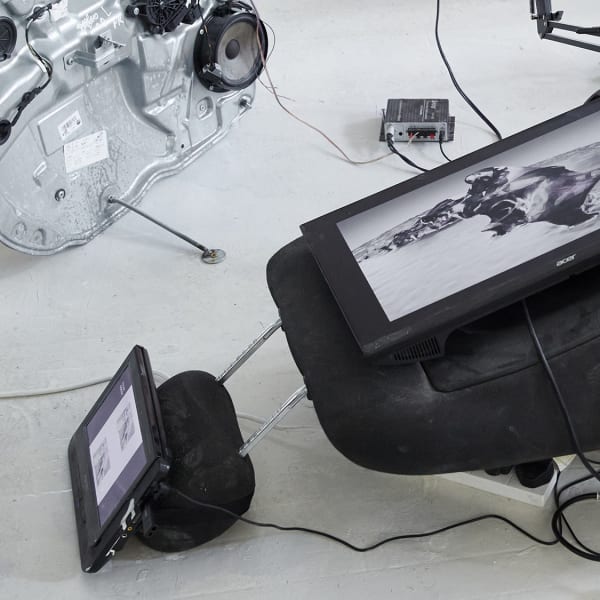 Car parts broken up across the gallery floor with digital screens added and inserted playing black and white images. Installation by Livia Harper - BA Fine Art