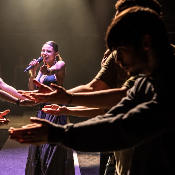 A group of performers holding their arms towards each other
