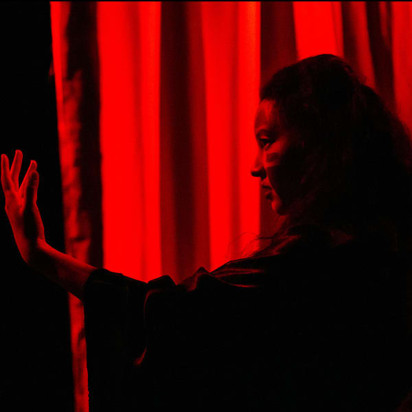 Dancer on stage under red light during the Design for dance project.