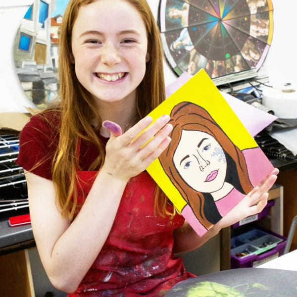 Girl holding up a painted self portrait.