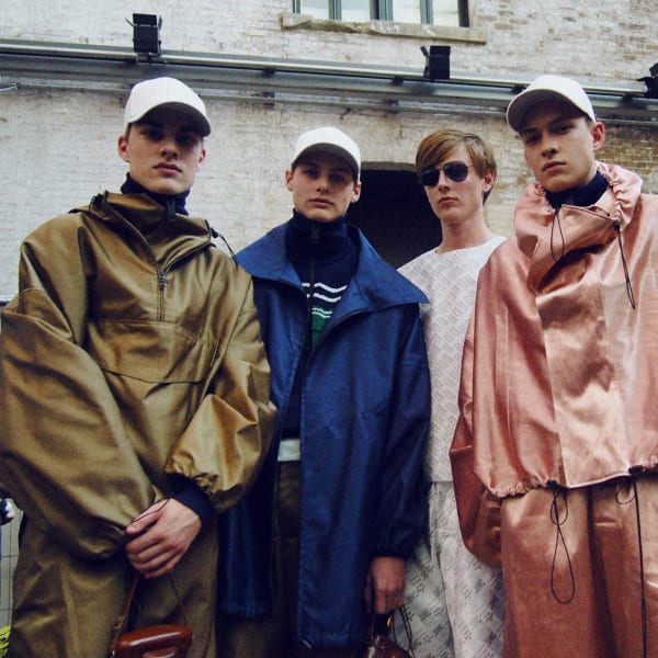 Five male models, some wearing baseball caps and some wearing sunglasses 