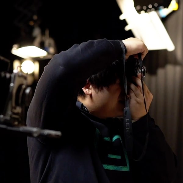 Close-up of a student holding a film camera in a studio.