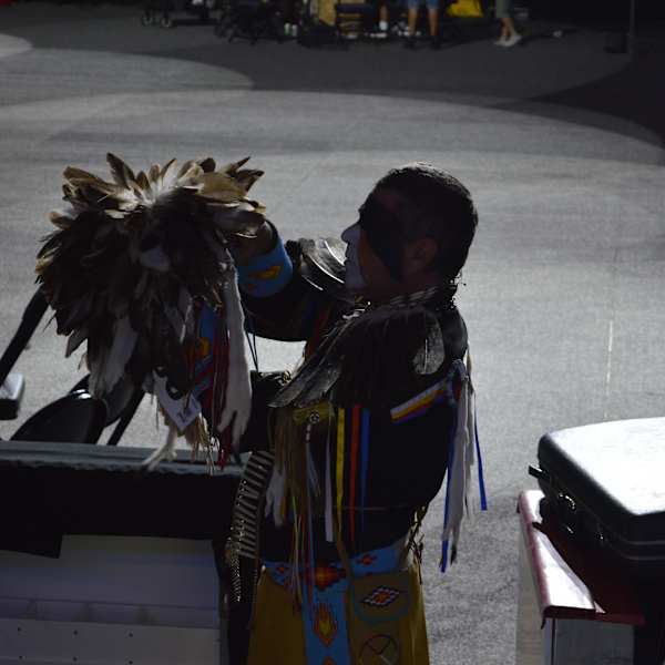 Photograph of a character on stage arranging a headress