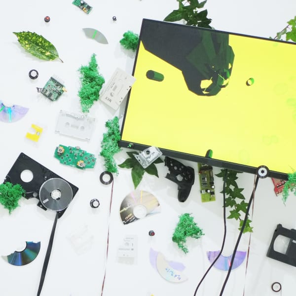 White wall with a screen surrounded by a series of objects, including a pair of headphones.