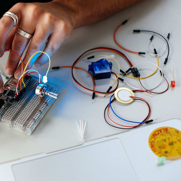 Close up image of student working with computational equipment, wires and light bulbs