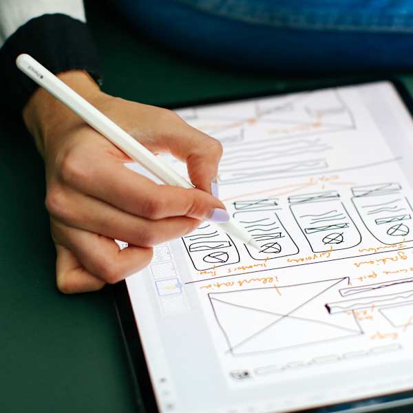 Photograph of someone taking notes on an ipad, against a green sofa.
