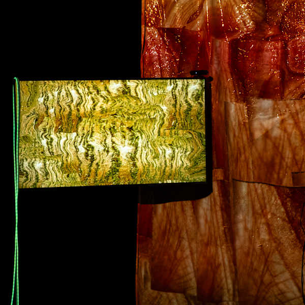 Headphones and a video screen within an illuminated installation of translucent orange fabric panels.