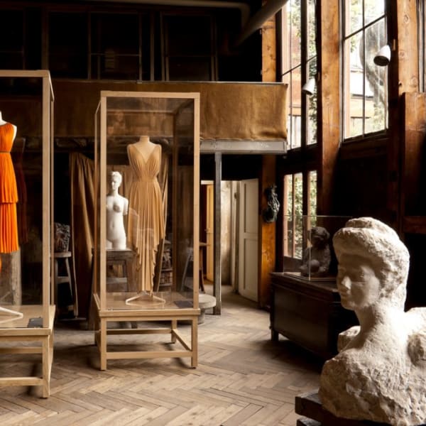 Dresses displayed in vitrines surrounded by shadowy statuary in a large room