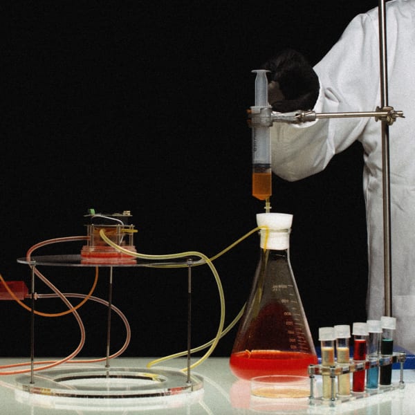 Two people wearing lab coats holding lab equipment