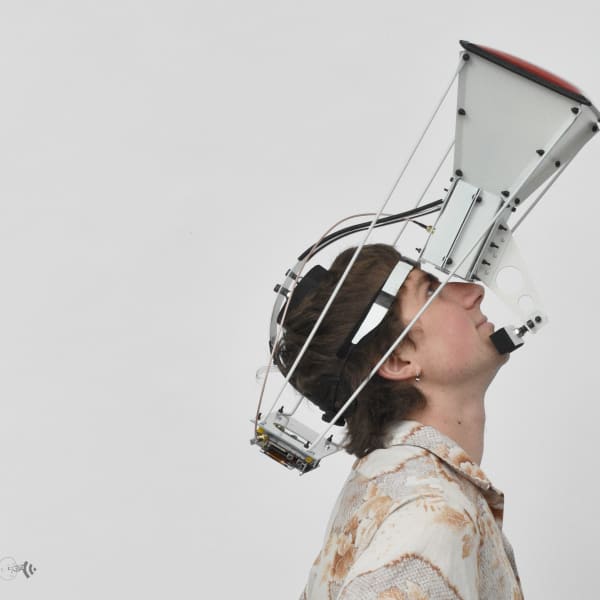 Young adult white male looks upwards into a metal construction strapped to his head
