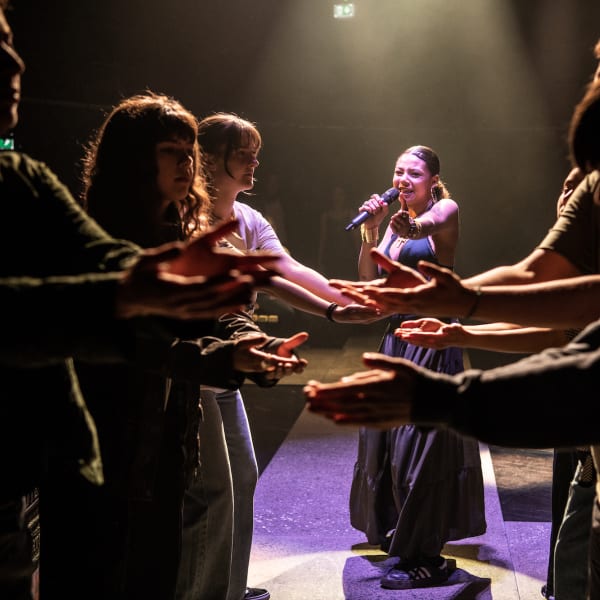 A group of performers holding their arms towards each other