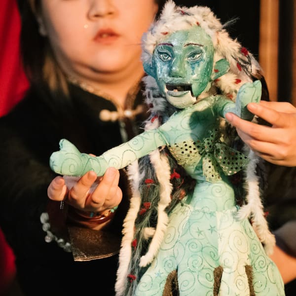 Two students holding a green puppet