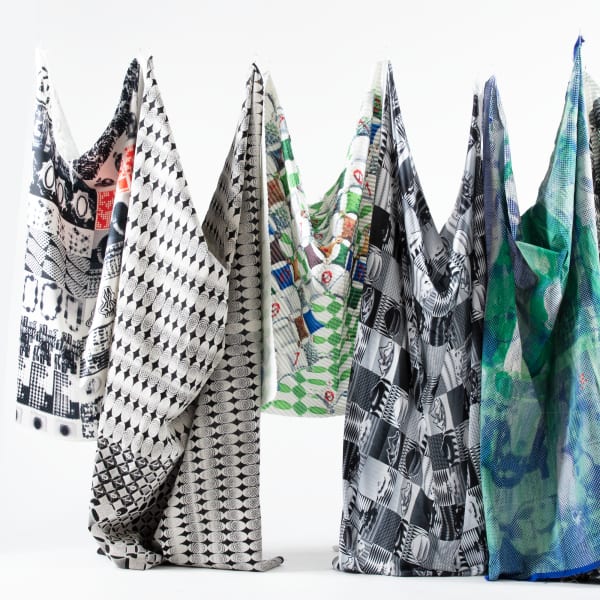 Six patterned fabrics hung from a white wall