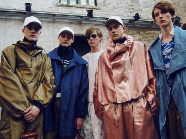Five male models, some wearing baseball caps and some wearing sunglasses 