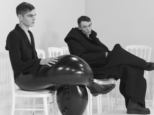 Four male models seated in loose black clothing