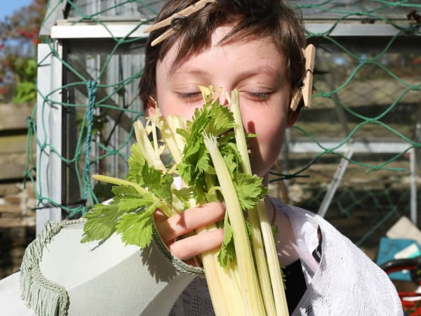 A girl holding a vegetable in front of her face 