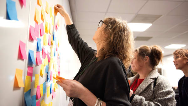 A woman sticking post-it notes to a wall