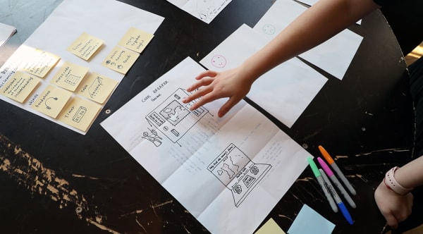 A table is filled with post-it notes, Sharpie pens and plans for a project titled: 'Code Breaker'