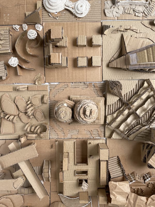 A birds-eye view of a series of cardboard 3D models, they could be buildings or places. 