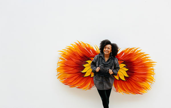 Woman standing in front of large orange and yellow flower graphic