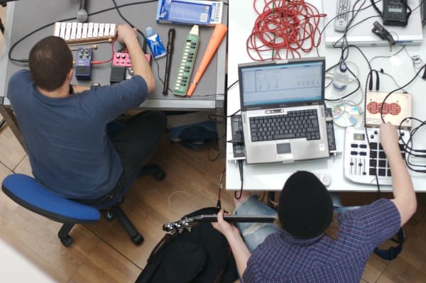 Birds eye view down on 2 students working with laptops, instruments and recording devices. 
