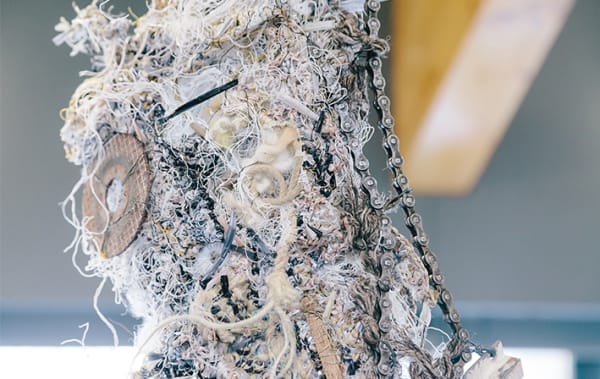 Different materials interwoven with unusual objects including a bike chain