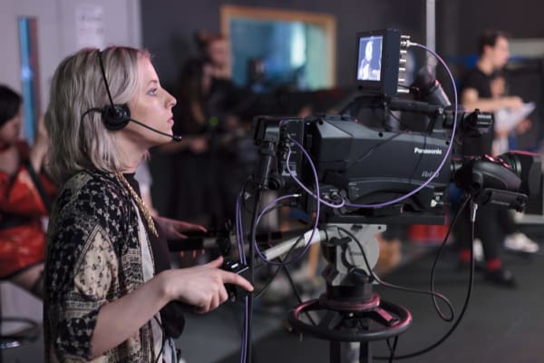 A young woman operating a television camera in a studio at London College of Communication