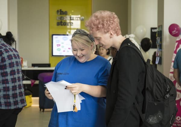 A woman standing next to a student offering him help