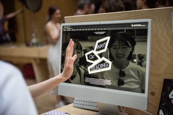A hand raised in front of a computer screen that reads 