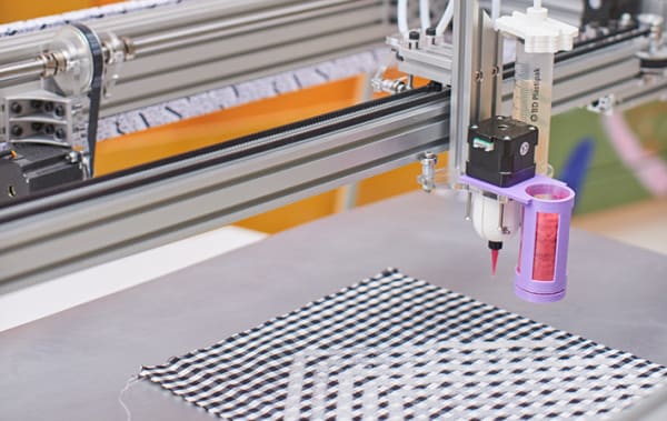 Detail image of a textile machine over a black and white material