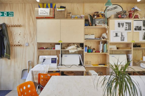back of a studio with shelves, tables, chairs and material lying around