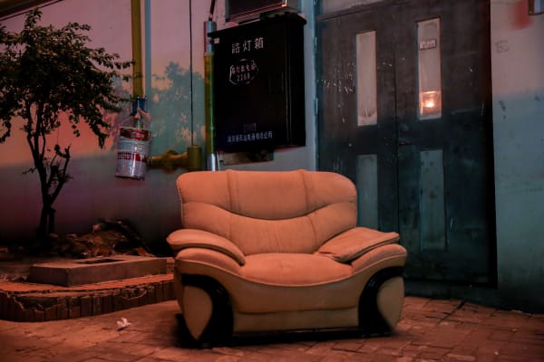 Photo of a large armchair in an outdoor setting, with Chinese script on a box on a wall behind 