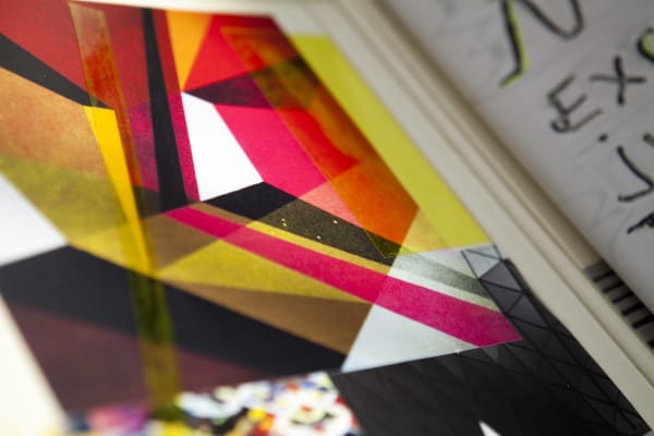 Abstract closeup of student sketchbook showing geometric red, yellow and pink shapes with a glimpse of handwriting