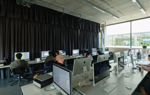 Two long desks each with rows of Mac computers.