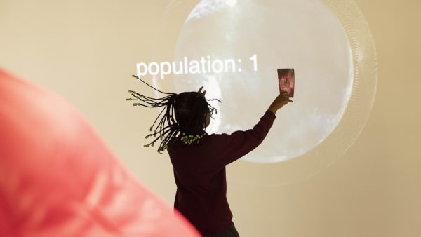 Girl dancing in front of a giant digital screen.